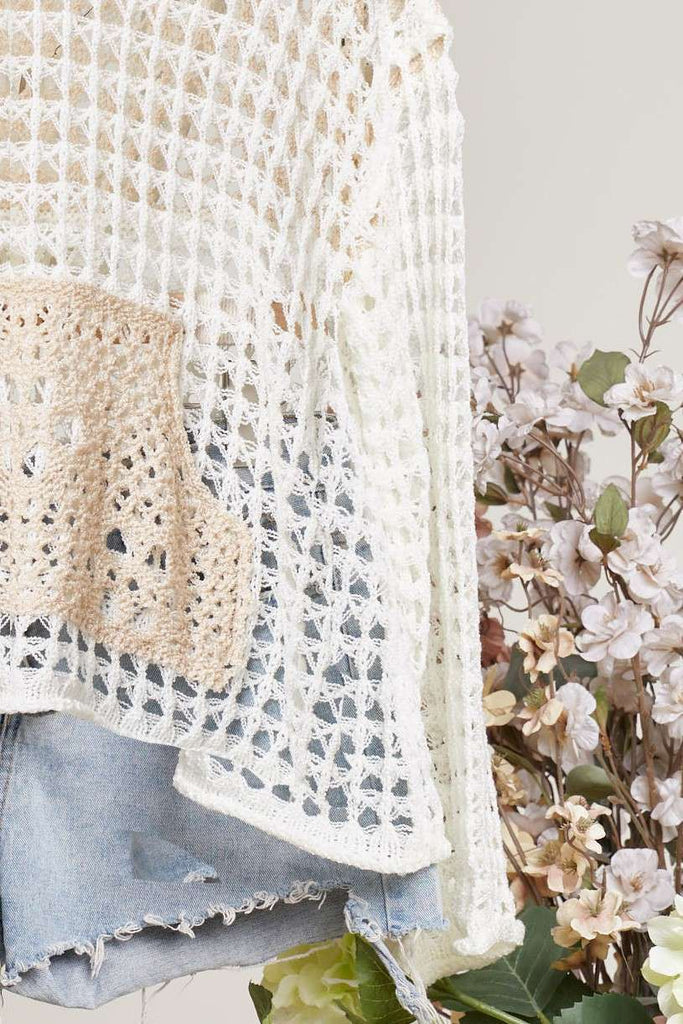 Close-up of a crocheted sweater with floral and denim elements on a light background