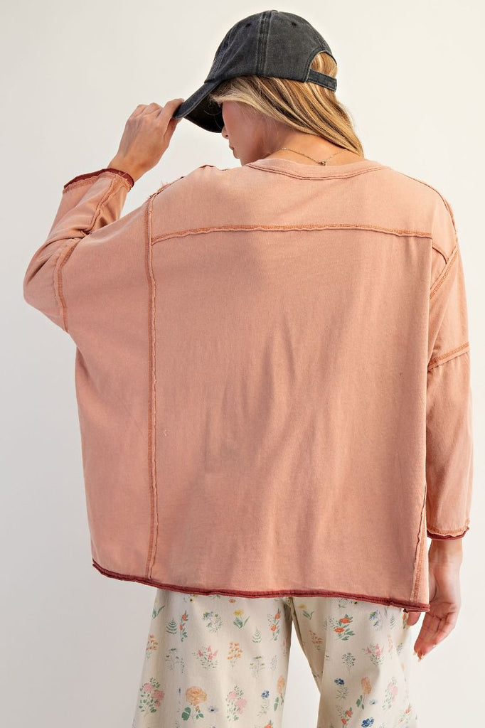 Person wearing a peach jacket and floral pants with a cap on a white background