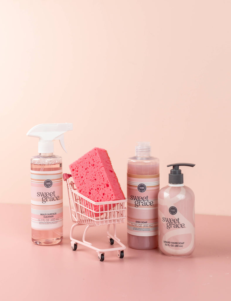 Bath and body products with a pink sponge in a small shopping cart on a pink background, featuring the brand 'Sweet Grace'.