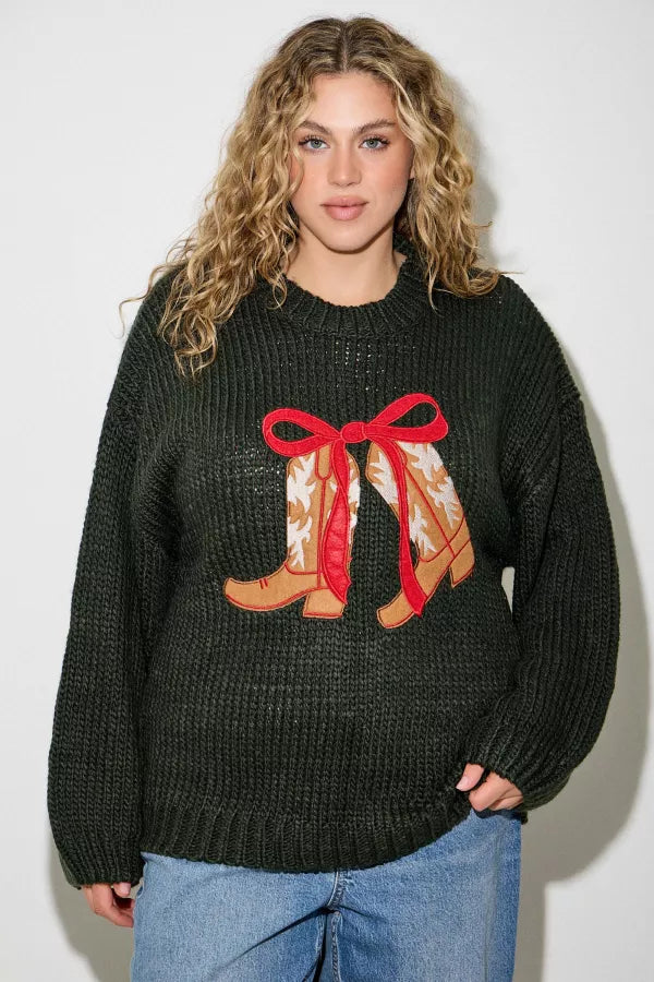 Model wearing Hadley Western Boot Sweater by Polagram in deep forest green featuring embroidered boots with red bow detail.