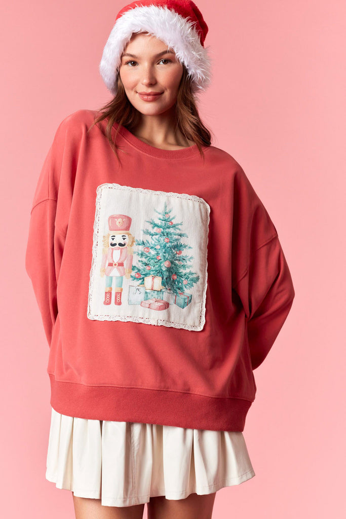 Person wearing a red sweater with a Christmas design and a Santa hat on a pink background