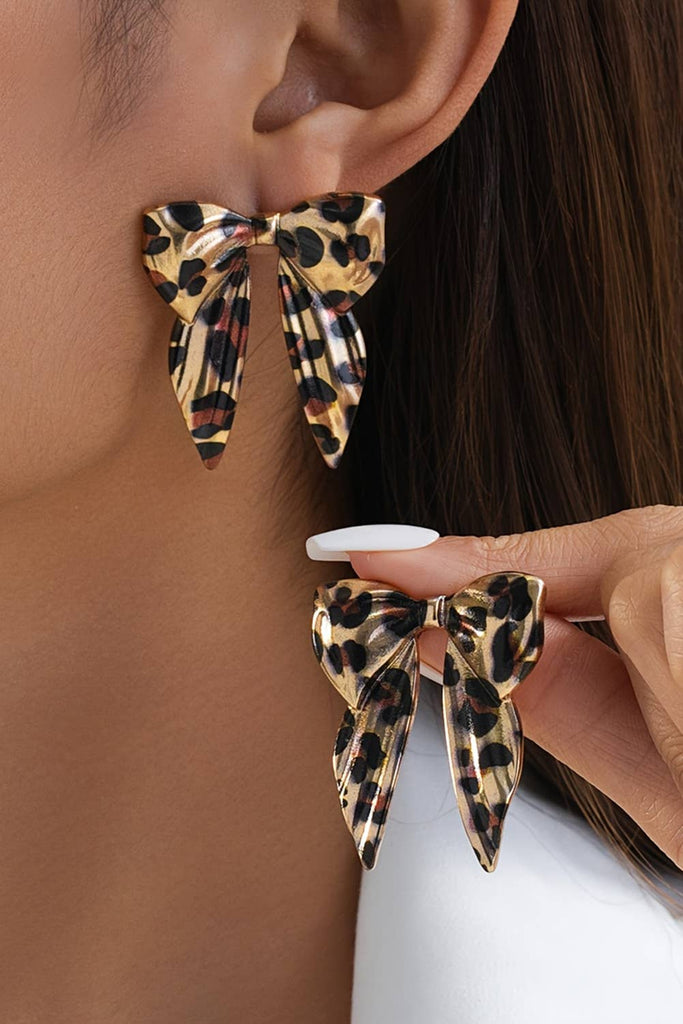 “Leopard print bow knot earrings in gold and black tones, boutique statement jewelry with playful bow design, lightweight alloy women’s accessory.”