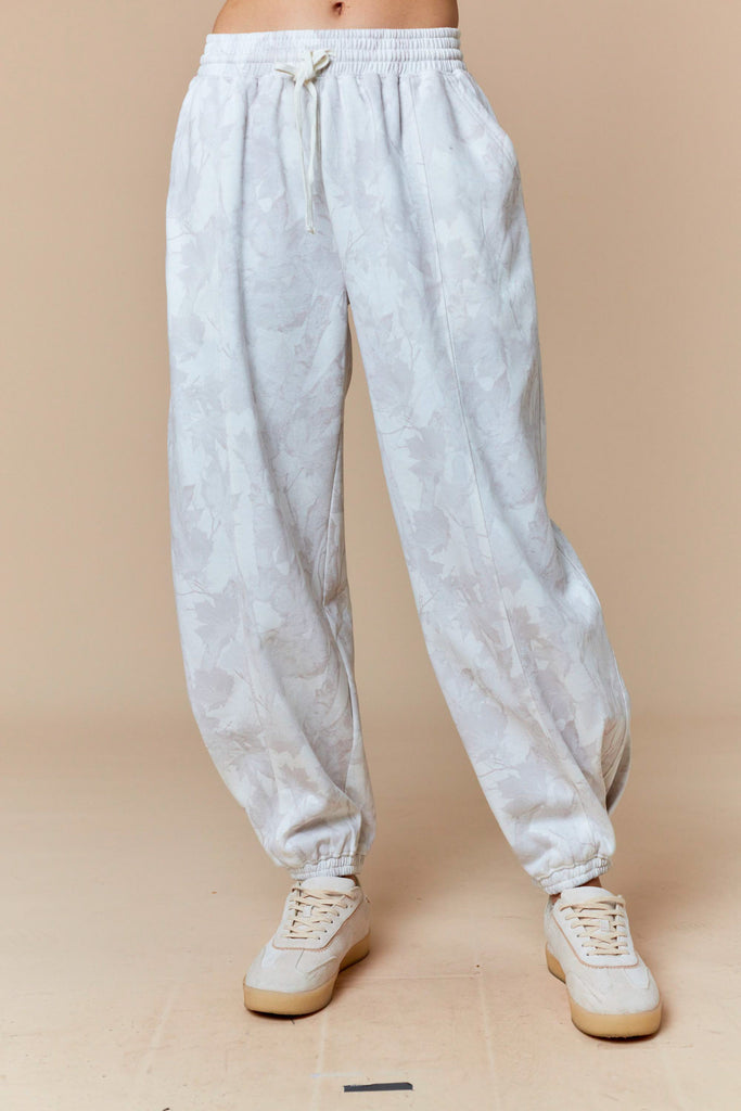 White and pale gray tonal leaf print jogger pants with elastic waist and cuffs, casual boutique loungewear.