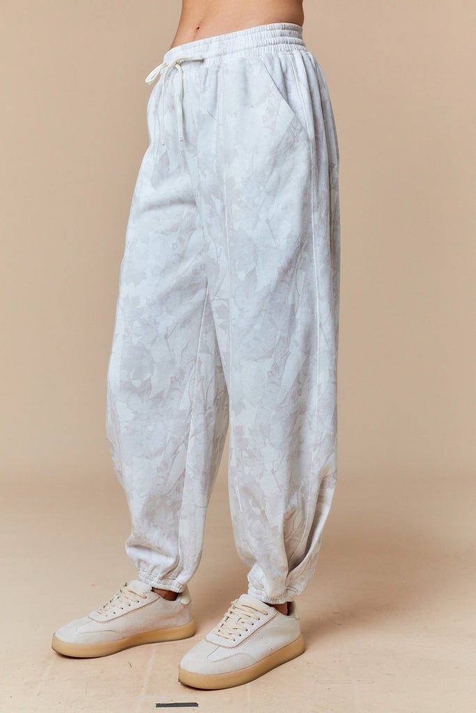 White and pale gray tonal leaf print jogger pants with elastic waist and cuffs, casual boutique loungewear.