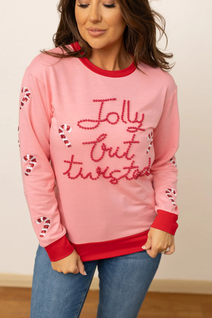 Tella Jolly But Twisted sweatshirt in pastel pink with a red sequin graphic and ribbed collar and cuffs, shown with a relaxed fit for a festive and fun look