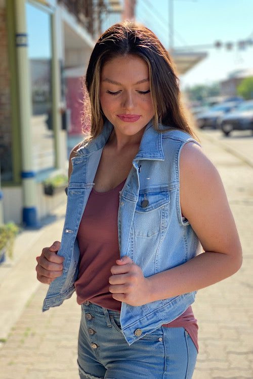 young woman wearing a boutique denim cropped vest  - looking down